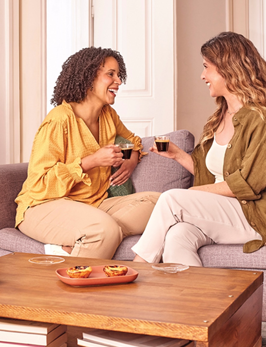 Two women in a living room drinking coffee together