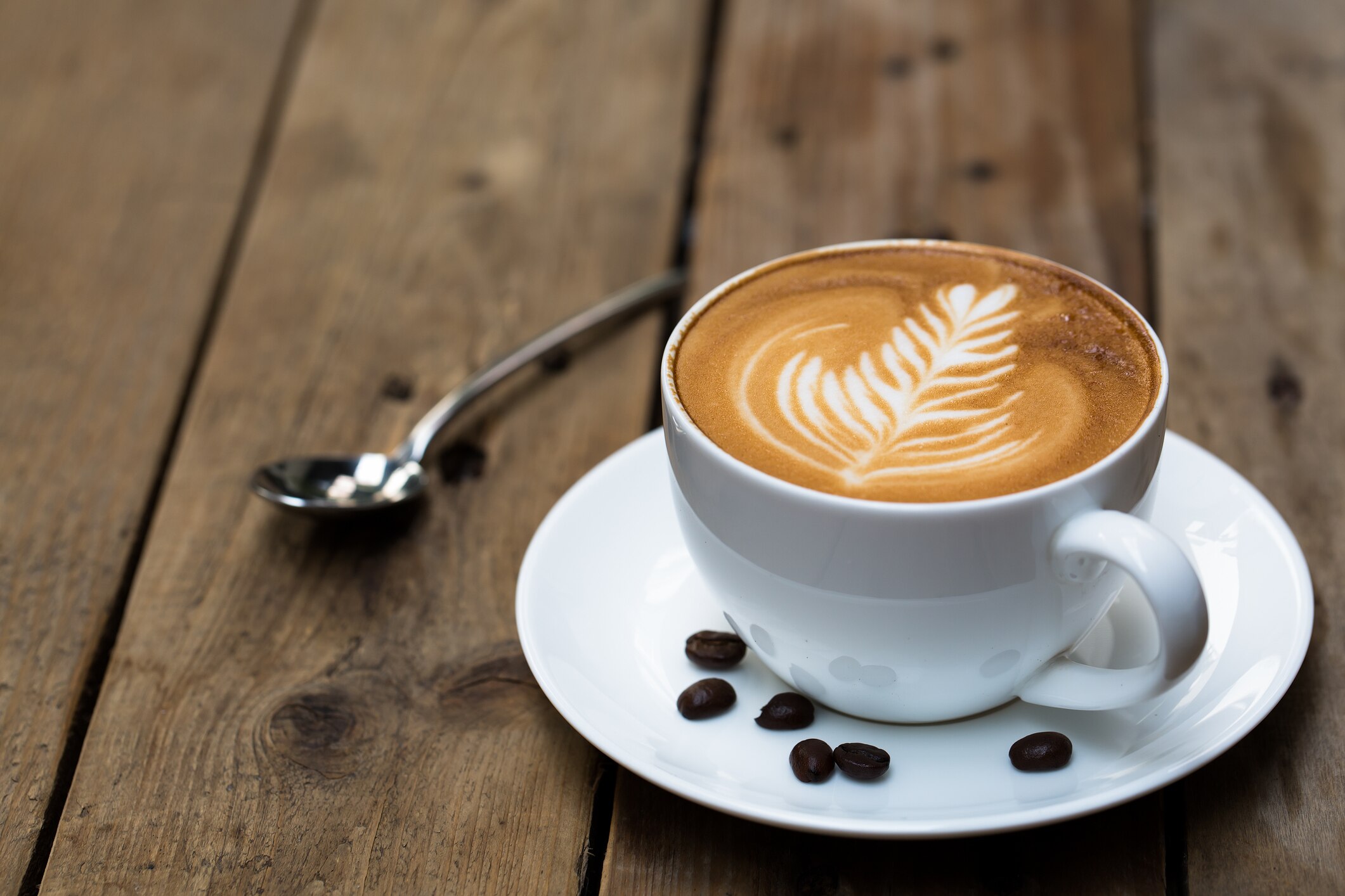 Mocha drink in a white mug with a teaspoon and saucer