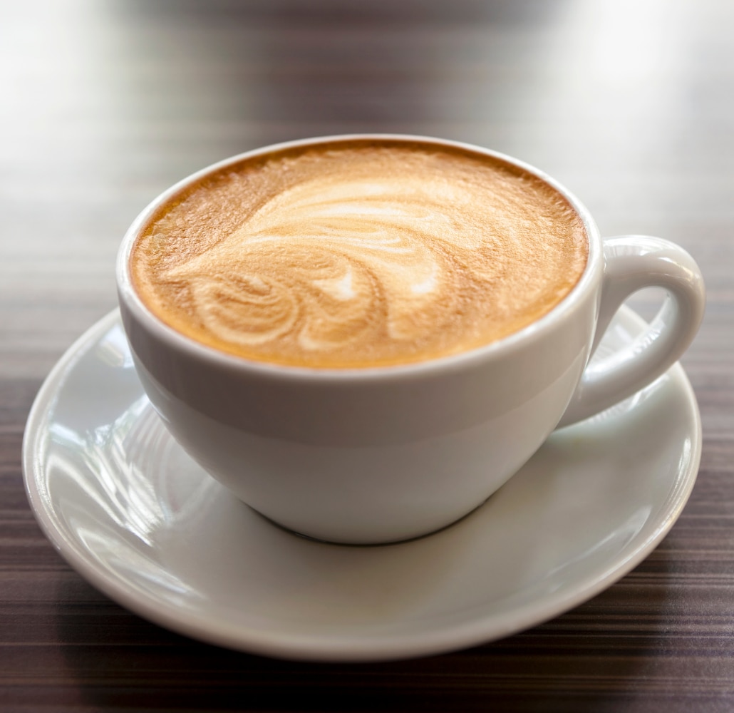 Flat white in a glass on a red saucer
