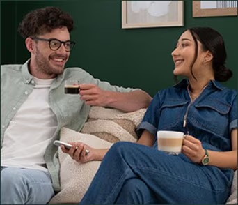 Two people enjoying coffee on a sofa.